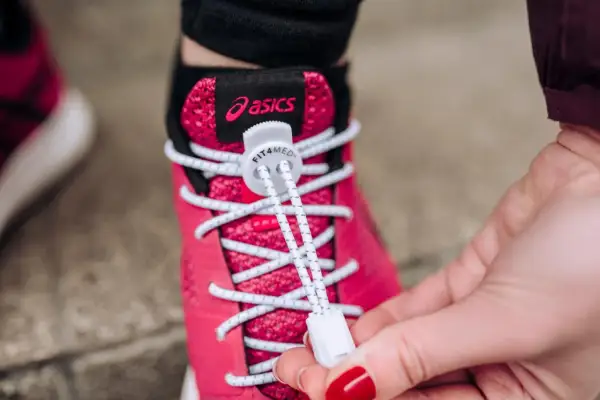 Różowe buty Asics z białymi sznurówkami wstążkami, które ułatwiają zakładanie.